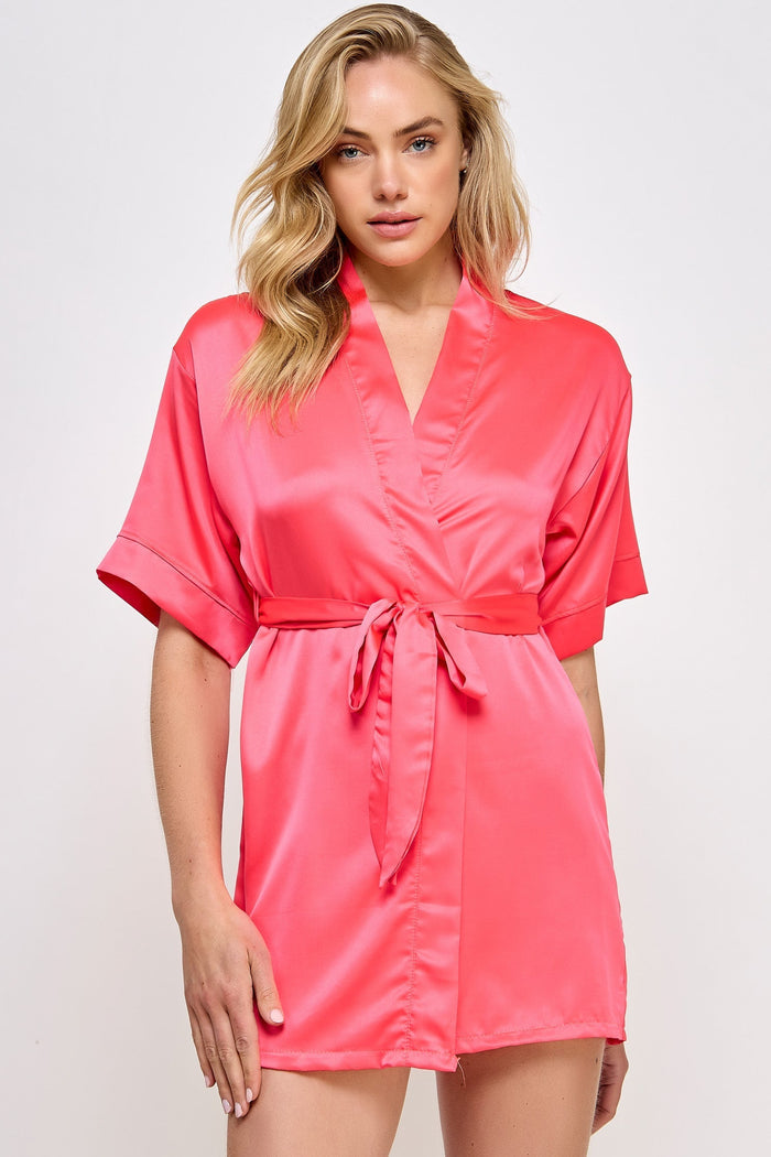 Woman wearing a pink satin robe against a white background