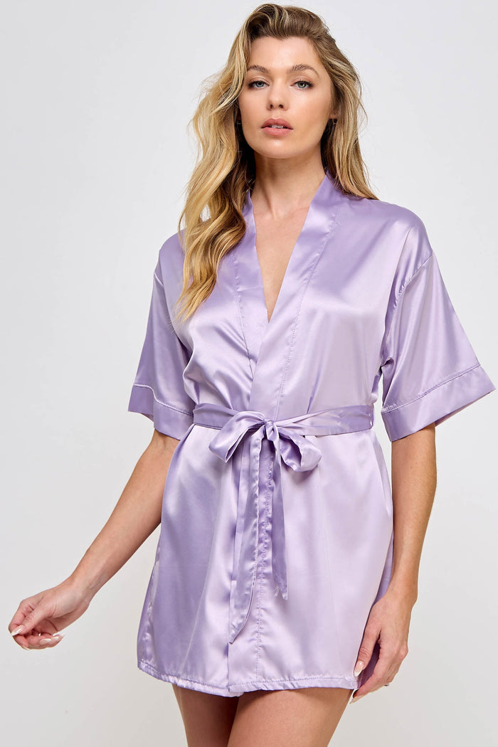 Woman wearing a light purple satin robe against a white background