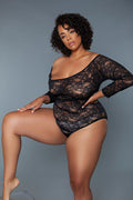 Woman wearing a black lace bodysuit against a gray background