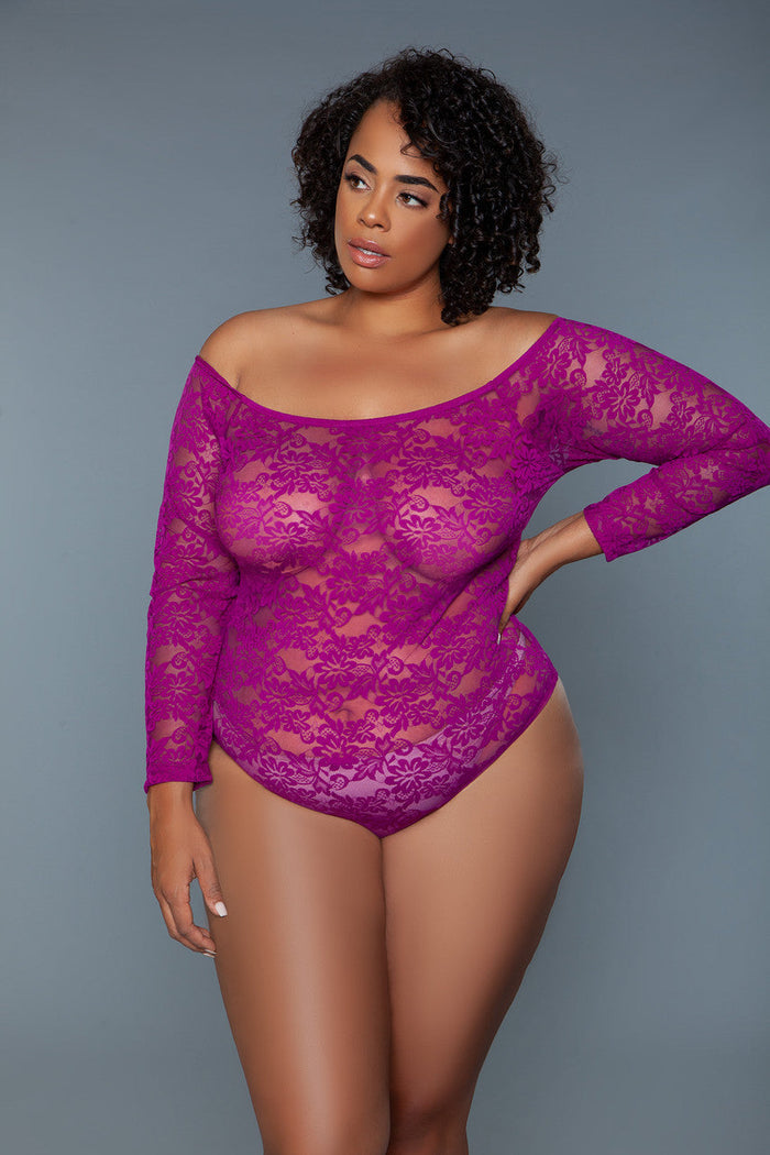 Woman wearing a purple lace bodysuit against a gray background