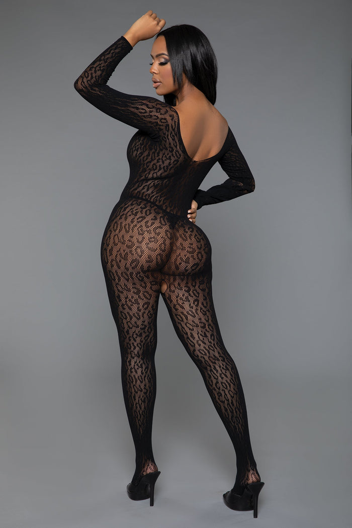 Model wearing a black lace bodystocking against a gray background