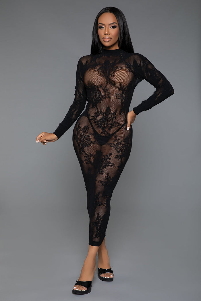Model wearing a black lace bodysuit against a gray background