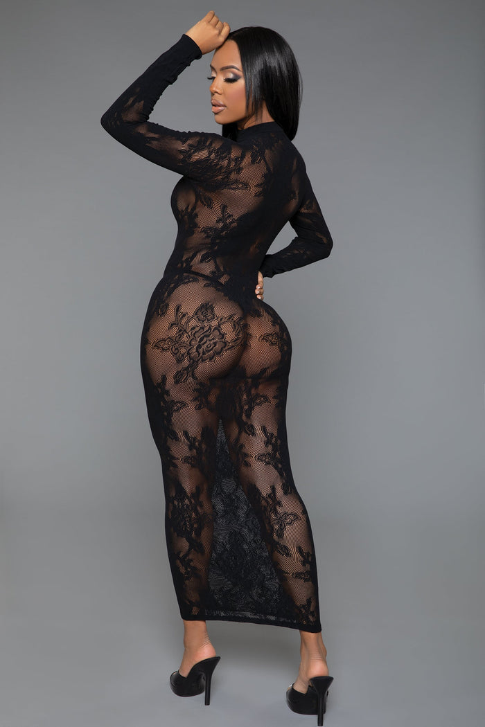 Model wearing a black lace bodysuit against a gray background