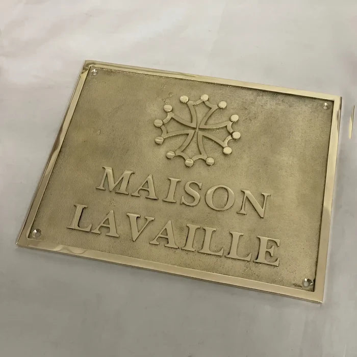 Brass plaque with 'MAISON LAVALLE' text and emblem on a light gray background