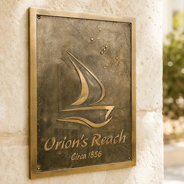 Custom bronze address plaque with sailboat design mounted on a light cream exterior wall