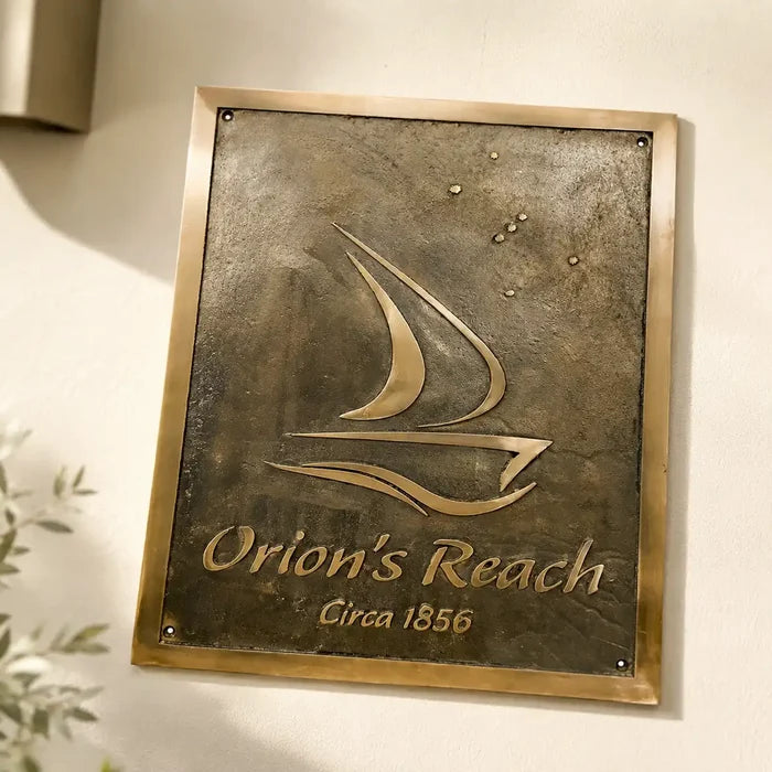 Close-up of personalized bronze plaque reading Orion’s Reach on a pale stone wall