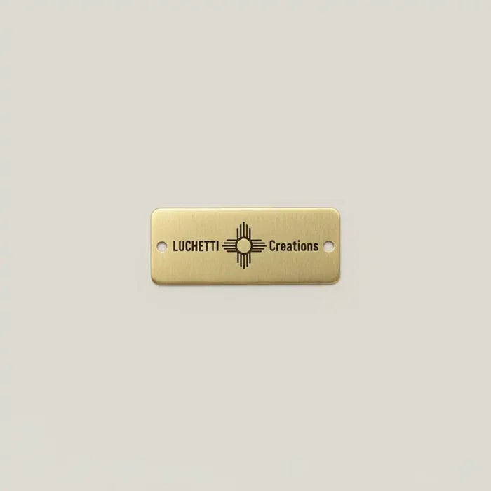 Gold rectangular tag with custom engraving on a light gray background