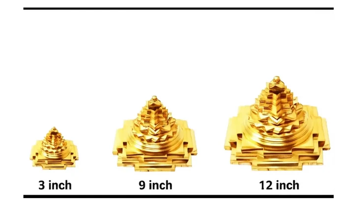 Three gold-colored Shiva Lingam statues of different sizes on a white background