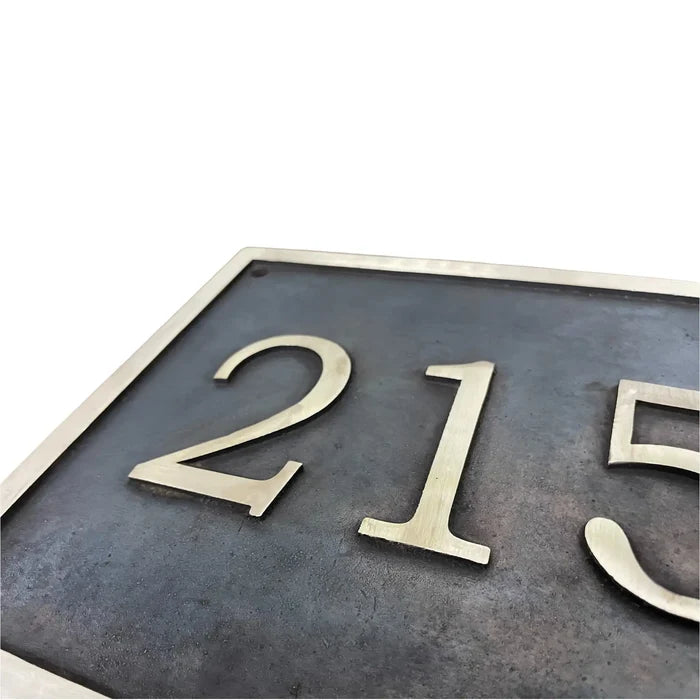 Brass house number plate with '215' on a white background