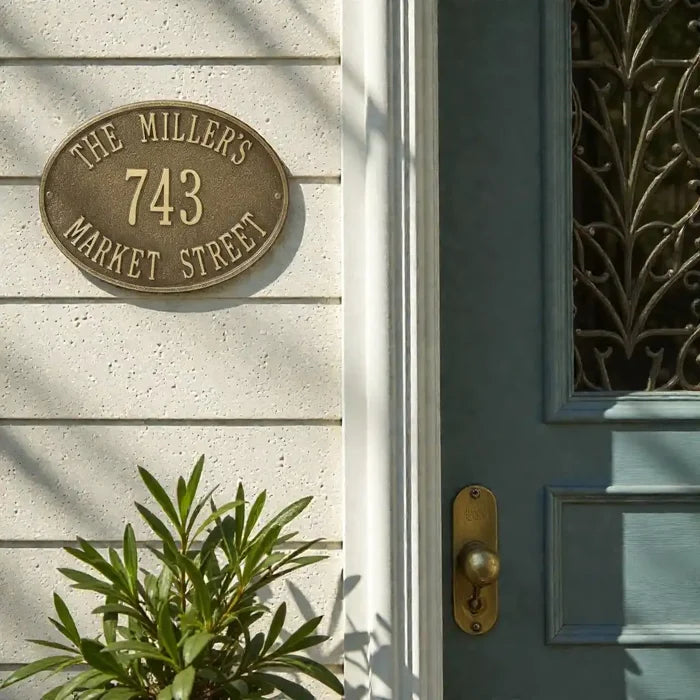 Address plaque on a house exterior with a door and plant in the foreground
