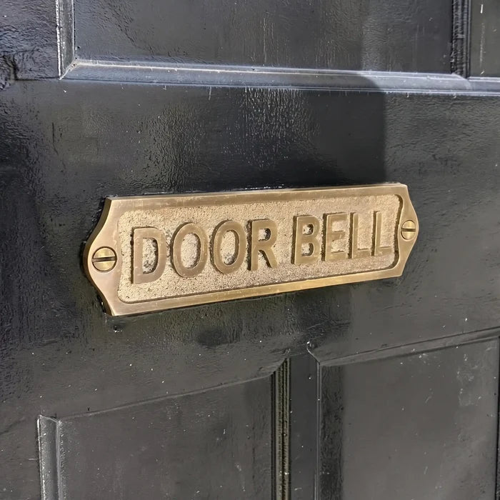 Brass doorbell plate on a black door