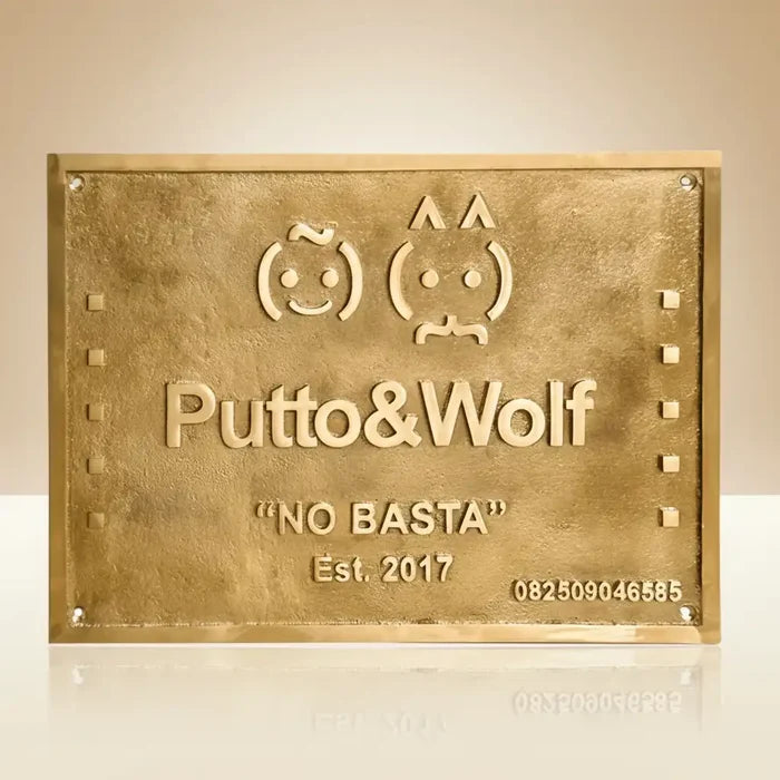 Brass plaque with custom branding and contact information on a beige background