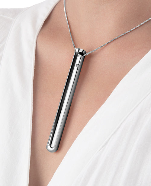 Silver pendant necklace on a person wearing a white top