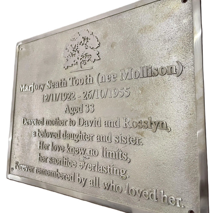 Brass plaque with engraved text and a tree design on a white background