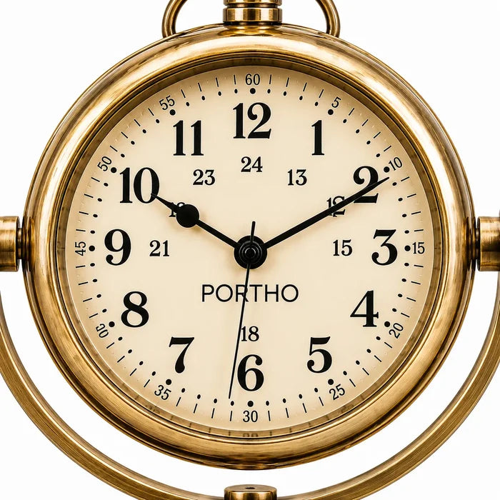 A close-up of a round analog clock with a polished gold brass case and a cream-colored dial. The clock features bold black Arabic numerals, black hands, and the brand name 'PORTHO' printed below the 12 o'clock position.