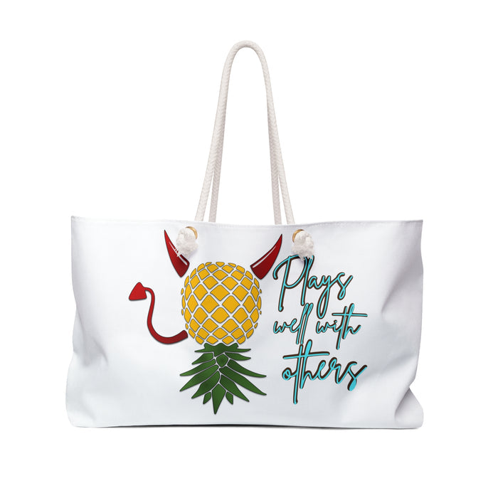 A white weekender bag with a playful pineapple design, featuring text and decorative details on the fabric.