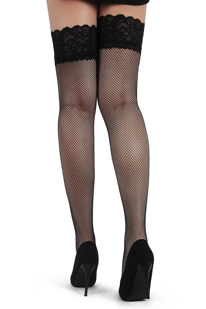 Black fishnet stockings with lace top worn with black high heels on a white background