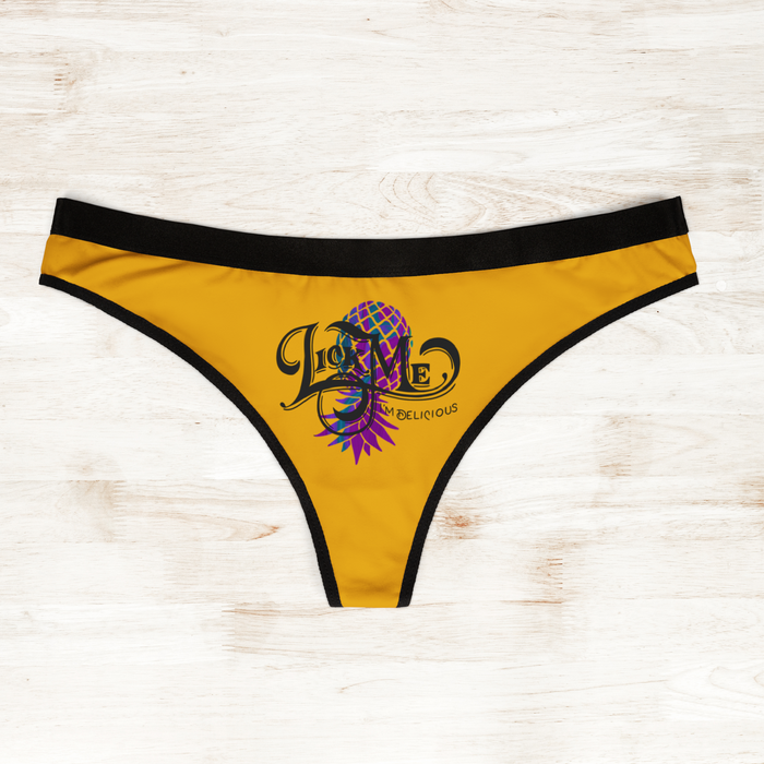 Yellow thong with black trim and colorful design on a light wooden surface